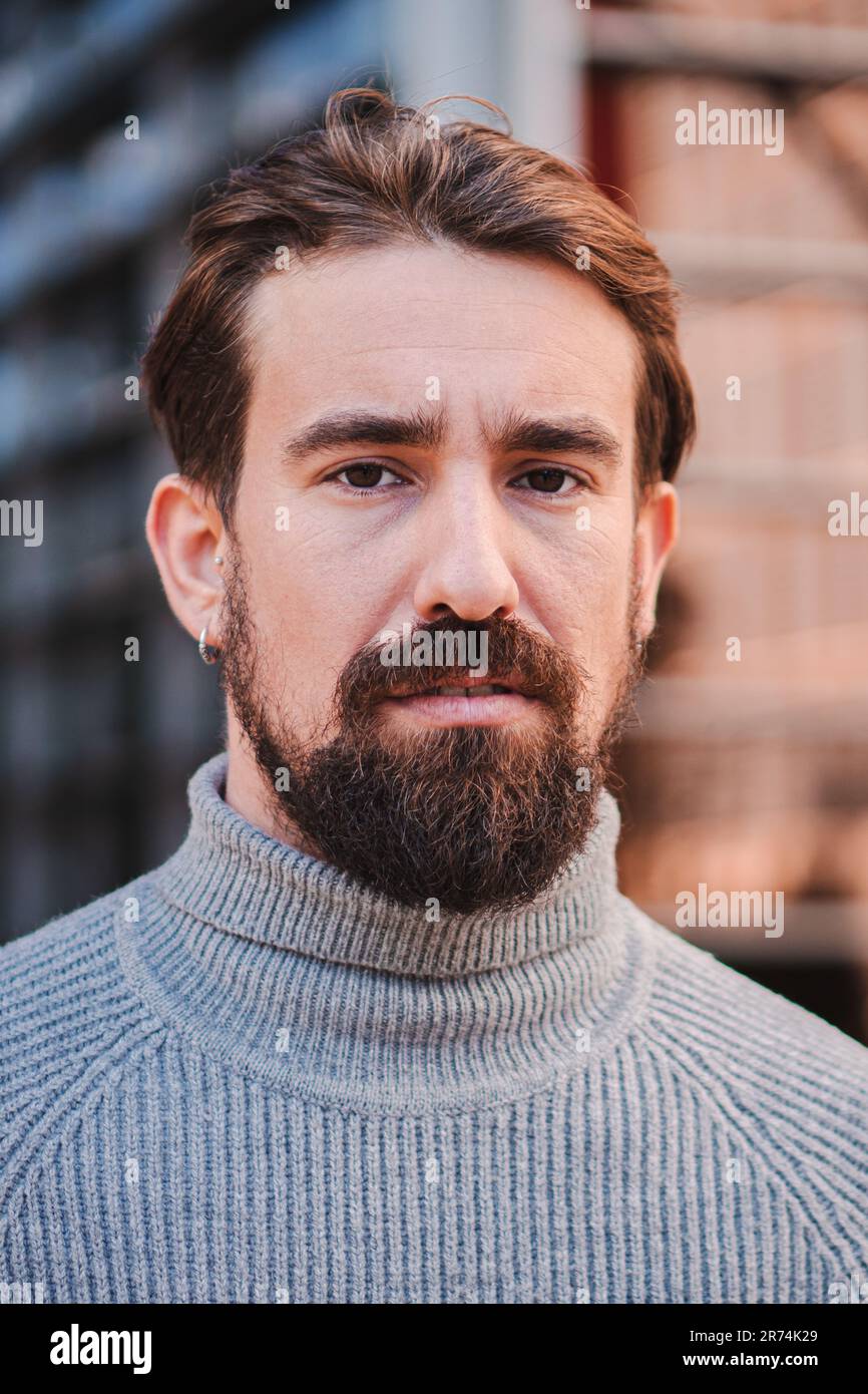 Vertikales Nahporträt eines jungen Weißen im Freien isoliert. Fotoaufnahme echter Emotionen männlichen Modells. Steht und sieht ernst aus. Gesichtsausdruck, menschliche Natur und Emotionsbegriff. Hochwertiges Foto Stockfoto