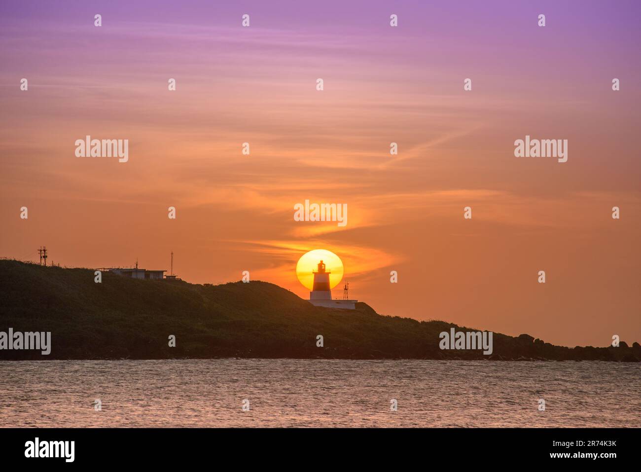 In der Dämmerung ist die Sonne hinter dem Leuchtturm. Das Fugui Cape Lighthouse in Shimen. Taiwan Stockfoto