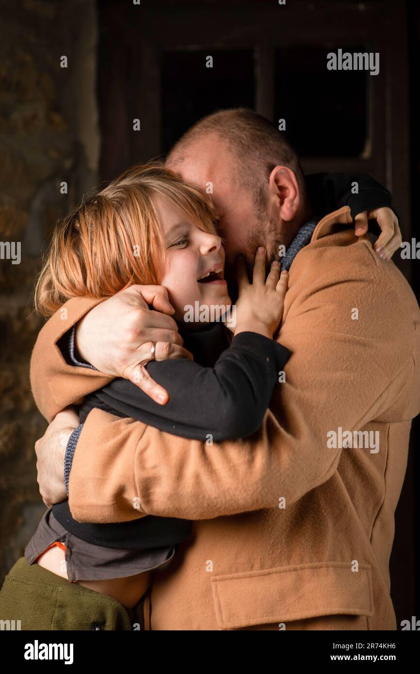 Ein Mann umarmt seinen jungen Sohn. Vatertag, das lange erwartete Treffen. Ein Mann mittleren Alters und ein neunjähriger Junge. Stockfoto