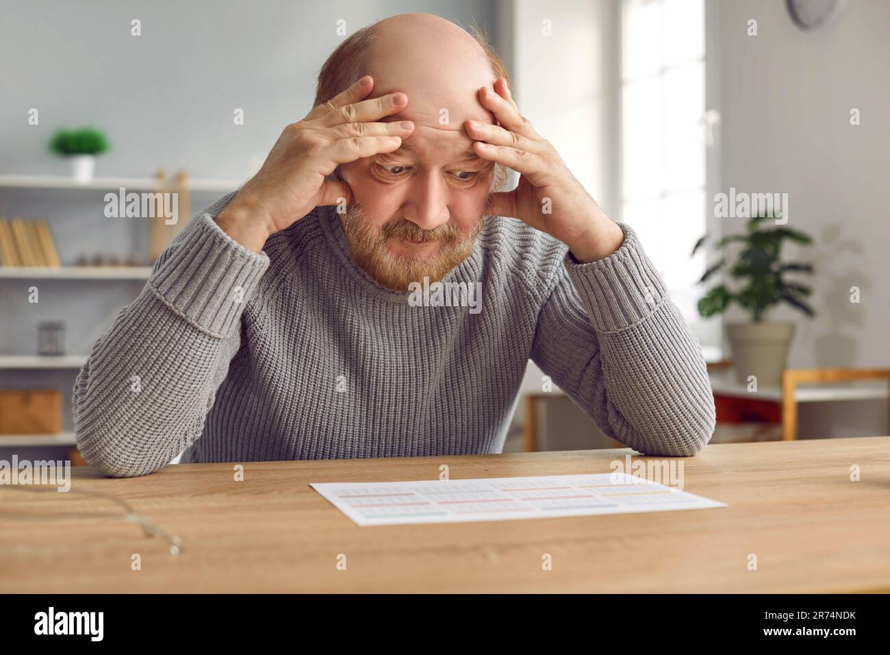 Ein älterer Mann mit Demenz verwirrt sich, wenn er Buchstaben und Zahlen im Kalender sieht Stockfoto