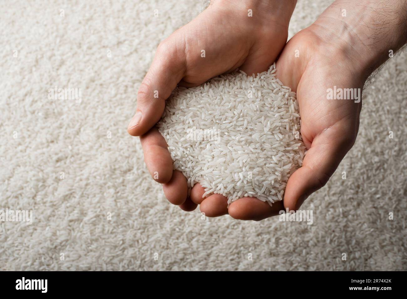 Menschliche Hände, die eine Handvoll Reis im Hintergrund halten Stockfoto
