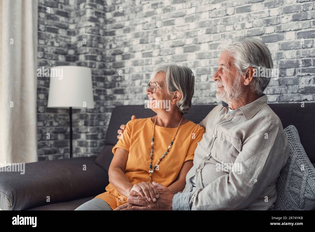 Glücklicher, reifer Mann und Frau sitzen zu Hause auf der Couch, umarmen und kuscheln, zeigen Fürsorge, lächelndes, liebevolles Seniorenpaar Entspannen Sie sich auf dem Sofa, genießen Sie ein zartes romantisches Familienwochenende zusammen Stockfoto