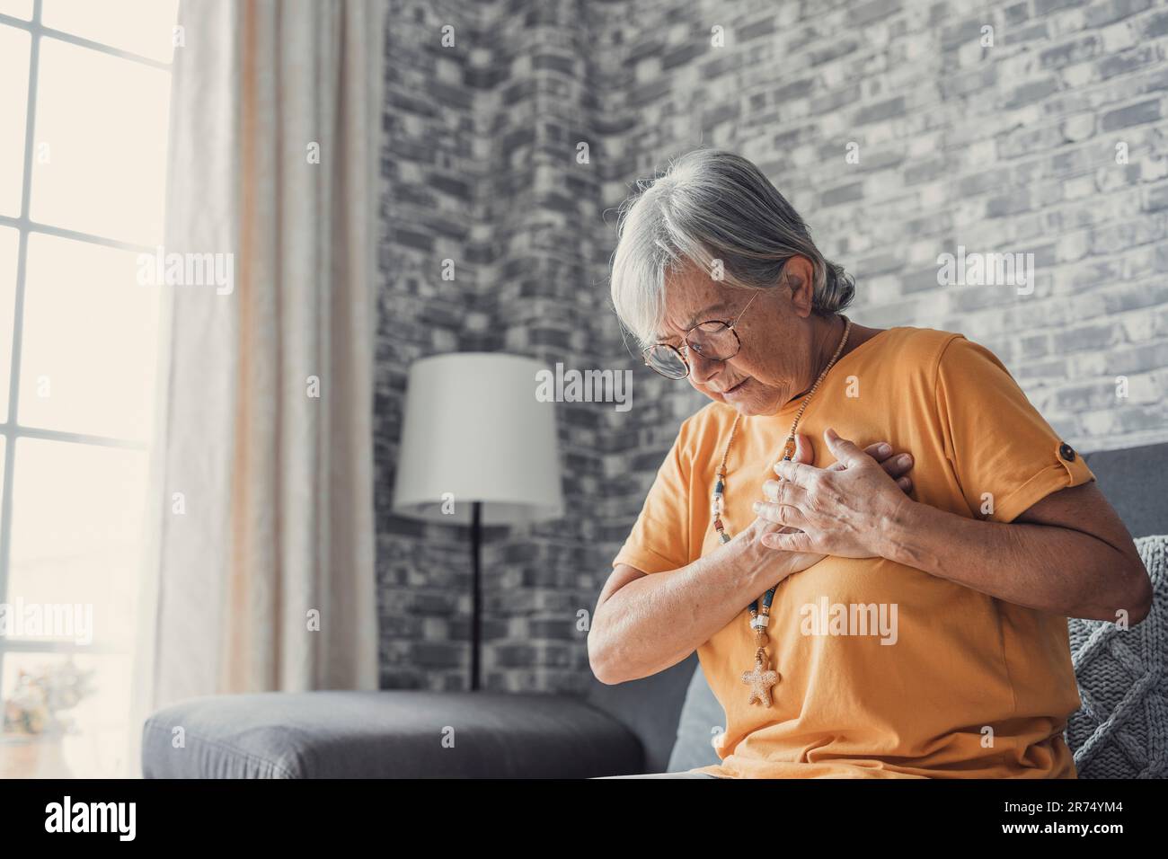 Gestresst reife Frau mittleren Alters Schmerzen Schmerzen Schmerzen berühren Brust hat Herzinfarkt, traurig besorgt ältere Dame leidet an Herzschmerzen zu Hause, Infarkt oder weibliche Herzkrankheit Konzept Stockfoto