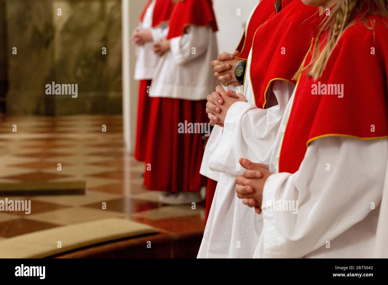 österreichische Altar-Kellner, Gefolgsleute, die in einer österreichischen Kirche beten, in rot-weißer Kleidung Stockfoto