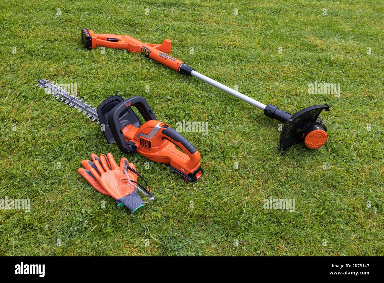 Die kabellose Heckenschere Black & Decker und die kabellose Rasenschere liegen auf dem Rasen, der Rasenpflege, dem Garten, Stockfoto