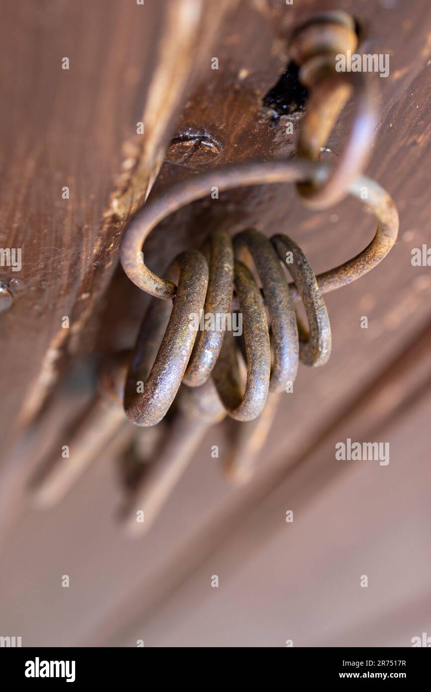 Alter rostiger Schlüssel im Schlüsselloch einer braunen Holztür, verschwommen, Stockfoto