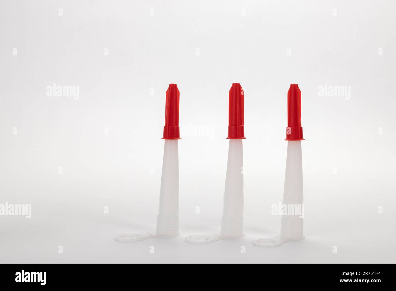Drei weiße Tüllen mit Kappe für Acryl- und Silikonkartuschen, weißer Hintergrund, Stockfoto