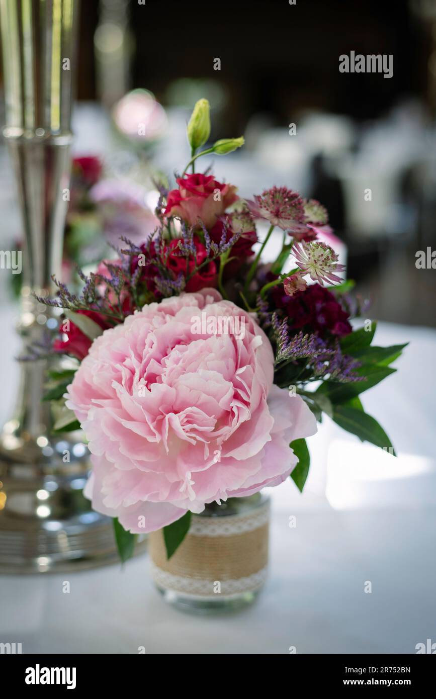 Blumenstrauß mit Pfingstrosen in einer kleinen Vintage-Vase auf einem festlichen Tisch Stockfoto
