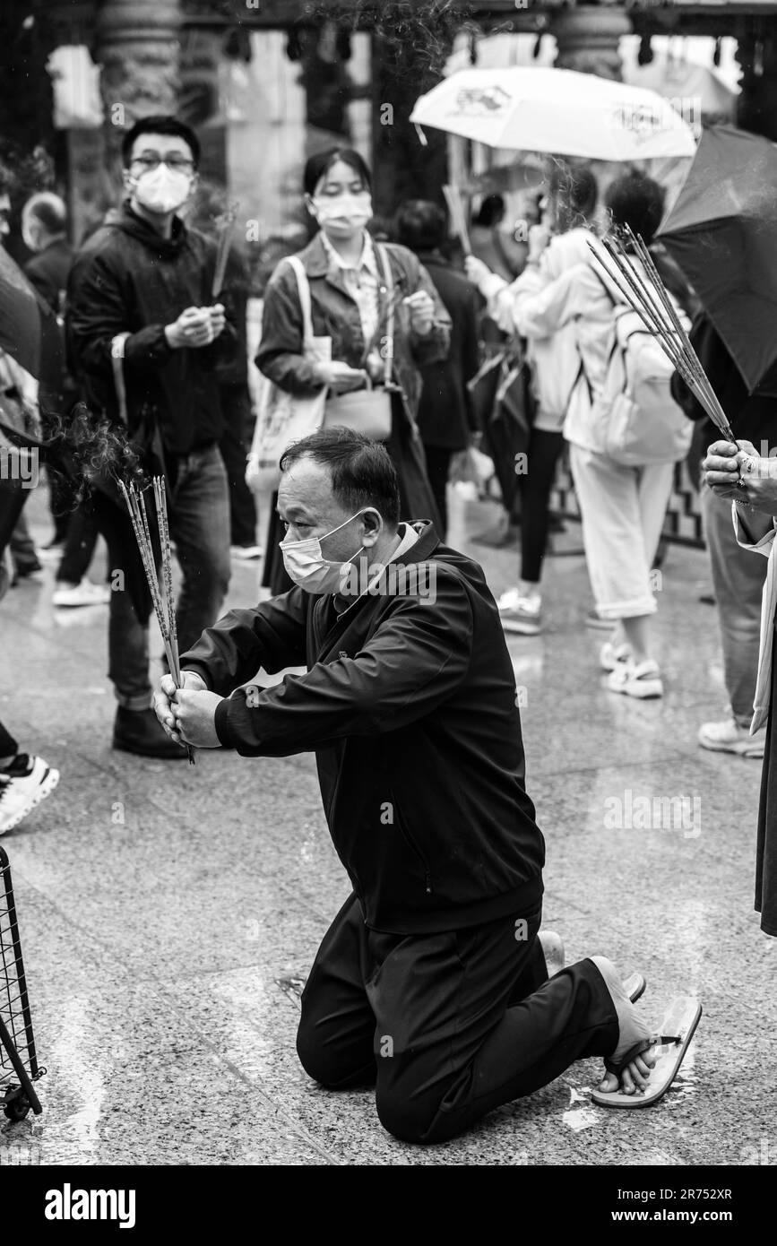 Ein hochrangiger chinesischer Mann, der im Wong Tai Sin Tempel, Hongkong, China anbetet. Stockfoto