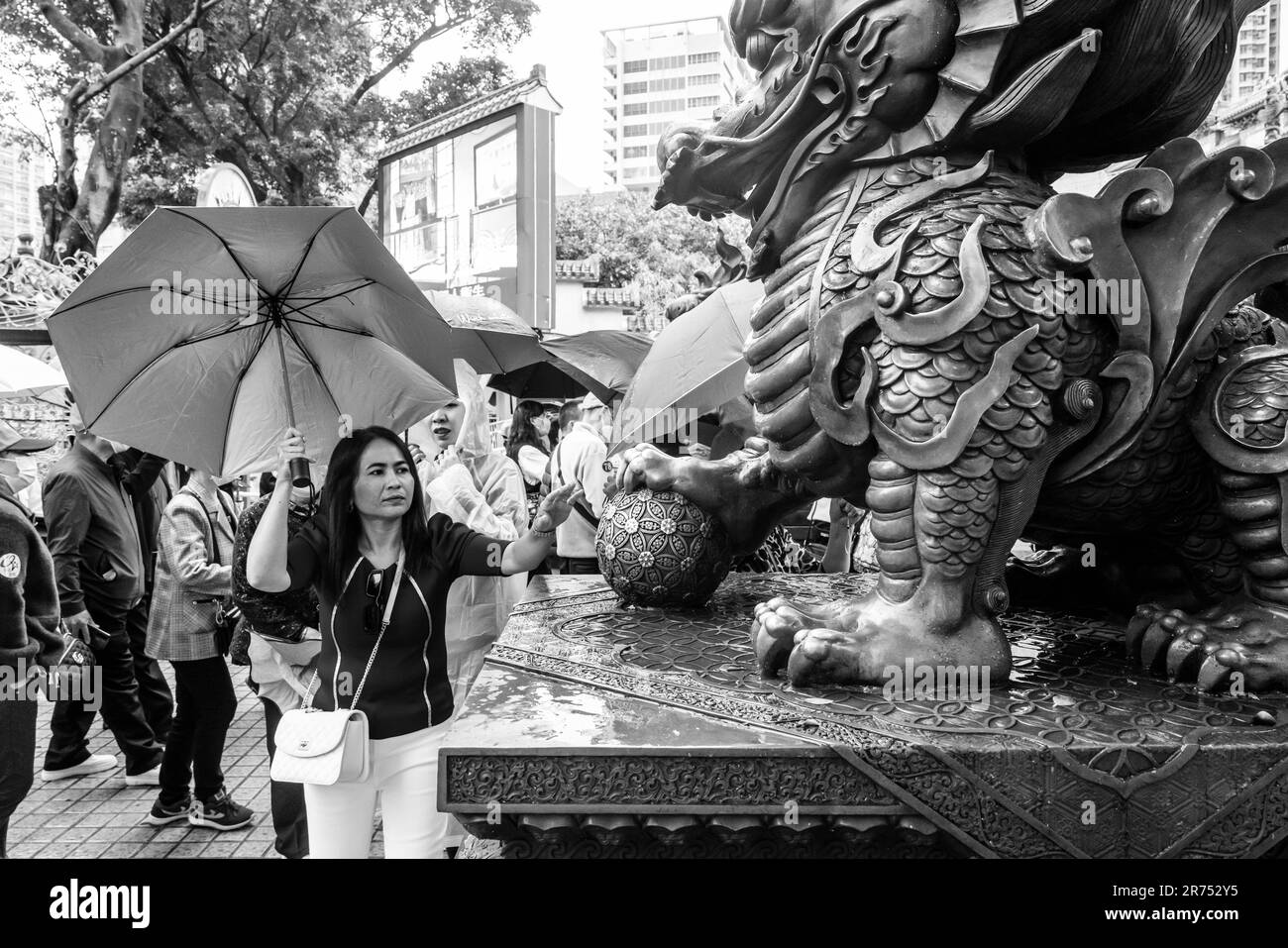 Eine Chinesin, die Eine Statue berührt, bringt Glück im Wong Tai Sin Tempel, Hongkong, China. Stockfoto