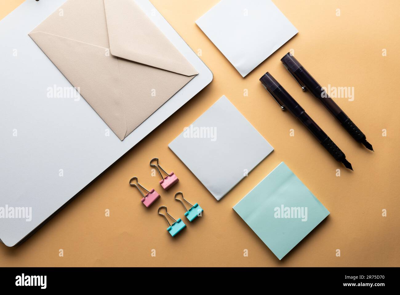 Flache Anordnung von schwarzen Stiften, Umschlägen, Büroklammern und Notizen mit Kopierbereich auf gelbem Hintergrund. Schulmaterial, Schreiben, Malen, Zeichnen, lear Stockfoto