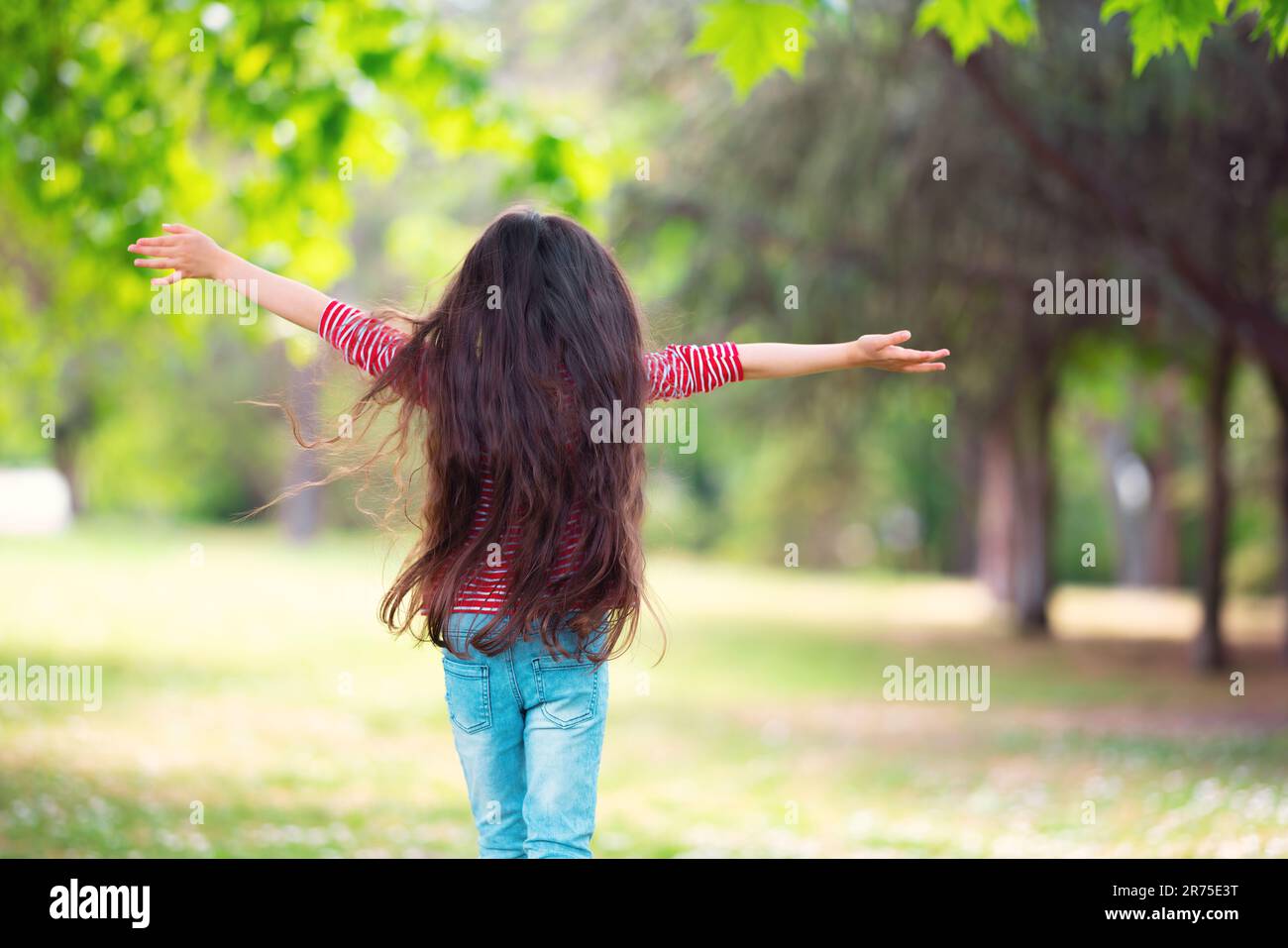 Glückliches kleines Mädchen, das draußen auf einem grünen Feld rennt, Abenteuer in einem Park, glückliche, langsam lebende Kindheit und Sommerurlaub Stockfoto