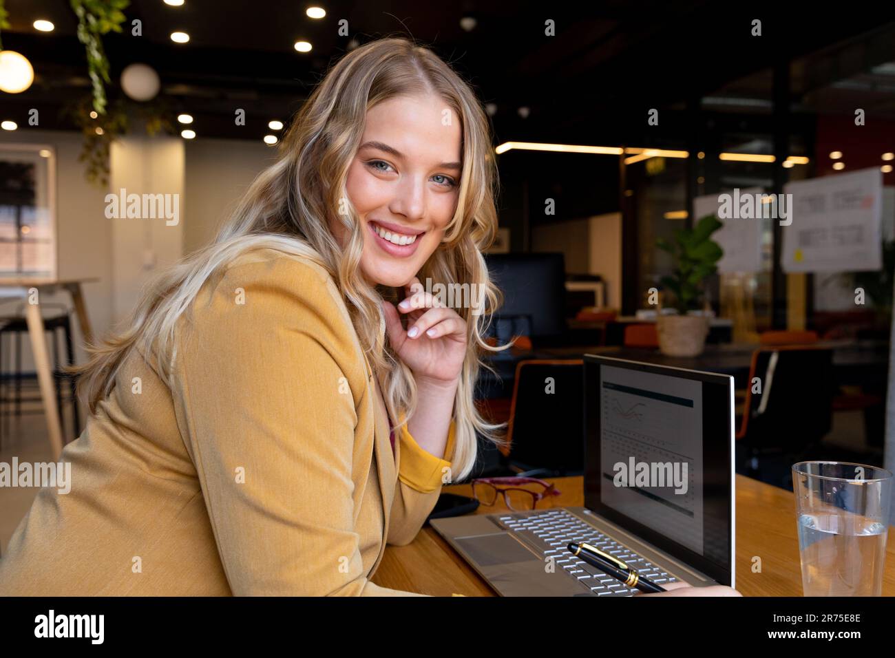Porträt einer glücklichen, übergroßen, weißen Geschäftsfrau mit Laptop am Schreibtisch Stockfoto