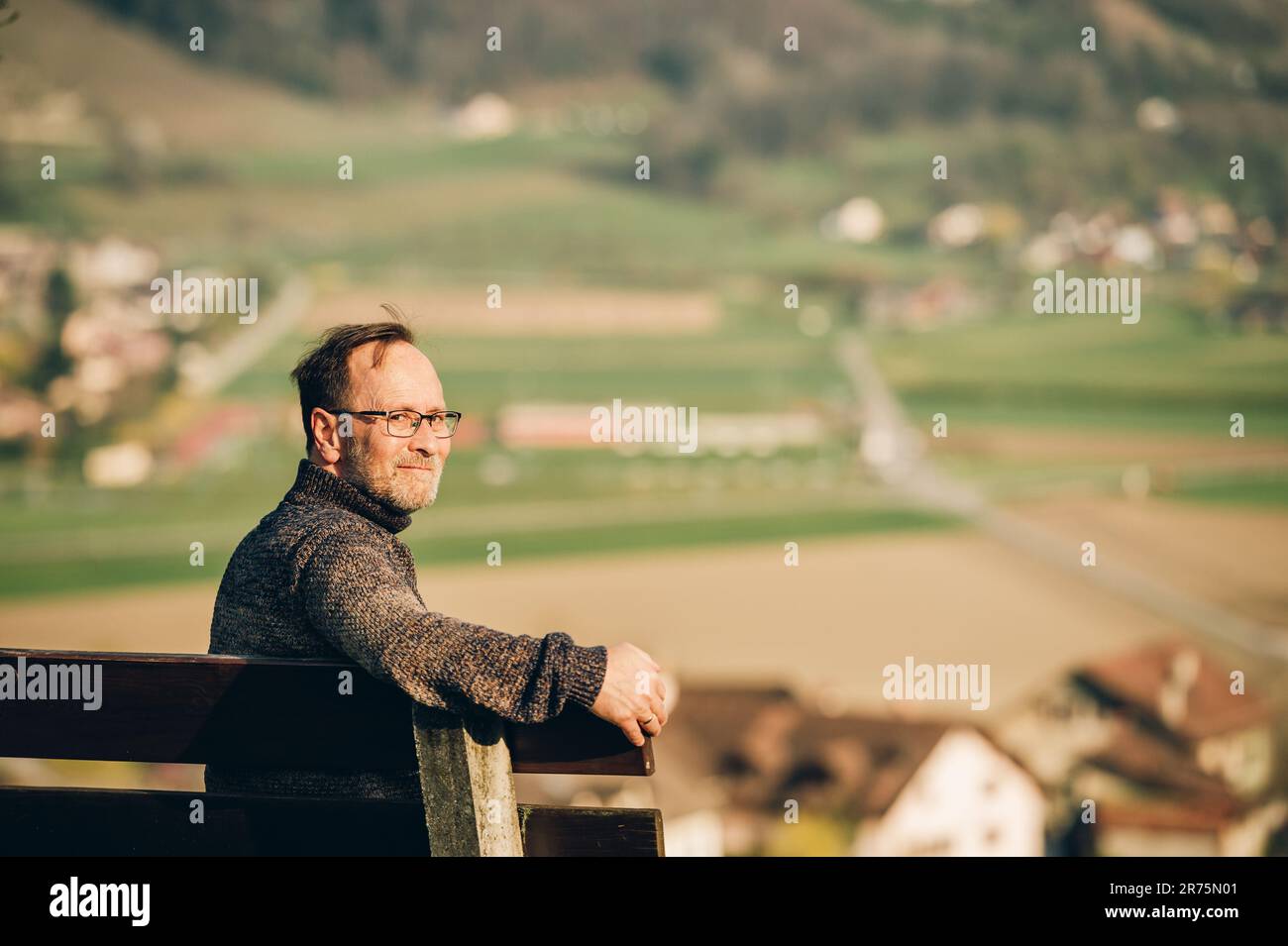 Ein Mann mittleren Alters, der an einem schönen sonnigen Tag auf der Bank entspannt, Bild aufgenommen in Wallis, Schweiz Stockfoto