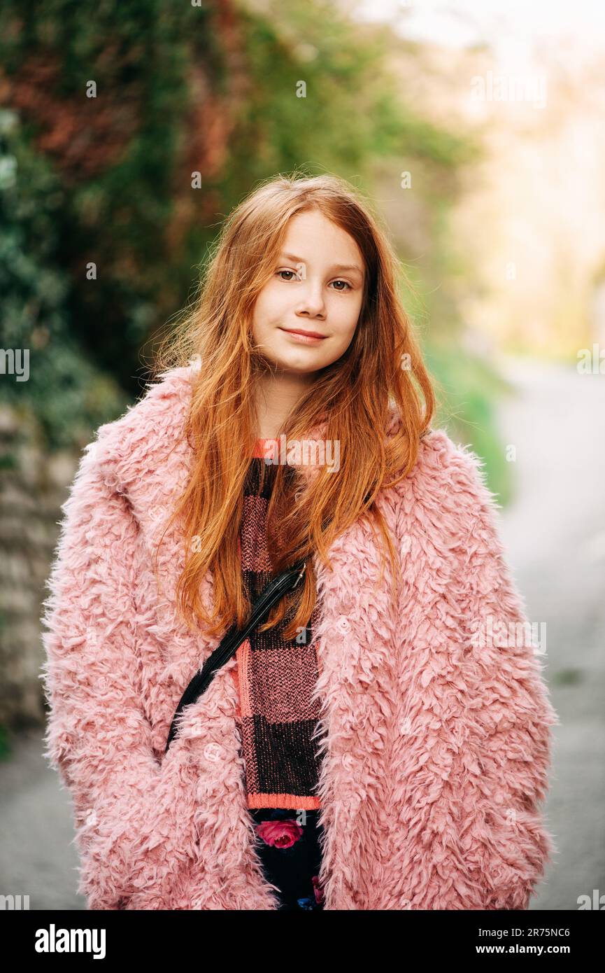 Nahaufnahme im Freien: Ein hübsches, junges rothaariges Mädchen mit pinkfarbenem, flauschigem Mantel Stockfoto