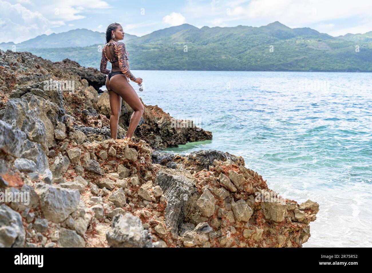 Nordamerika, Karibik, Großantillen, Hispaniola, Dominikanische Republik, Provinz Sama, Halbinsel Sama, Las Galeras, Playa del Amor, dunkelhäutige Latina, die auf einem Felsen am Meer steht Stockfoto