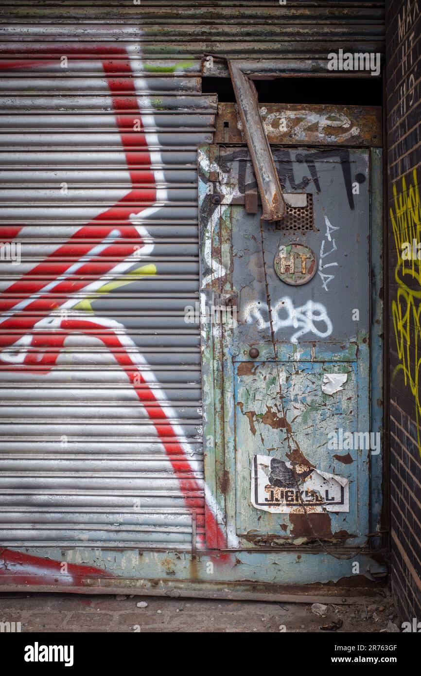 Eine Nahaufnahme einer Außentür in einer urbanen Umgebung, die mit Graffiti bedeckt ist. Stockfoto