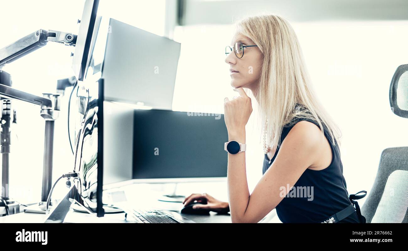 Weibliche Finanzverwalterin, die online handelt, sich Diagramme und Datenanalysen auf mehreren Computerbildschirmen ansieht. Moderne Geschäftsfrau conce Stockfoto