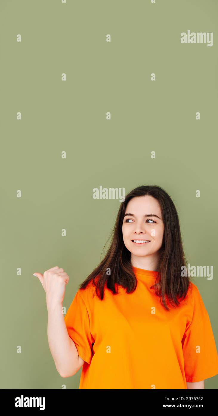 Fröhliche Dame, die auf leere Werbeflächen zeigt. Isoliert auf grünem Hintergrund. Perfekt für Marketing- und Werbekonzepte Stockfoto