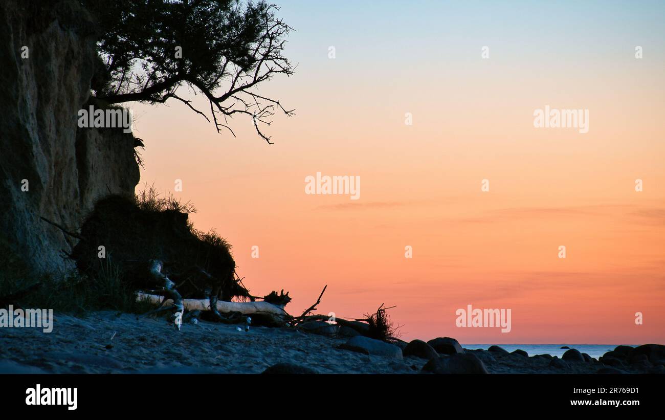 Steile Küste auf der Insel Poel bei Sonnenuntergang mit Blick auf den pastellfarbenen Himmel über Felsen in der Ostsee. Landschaftsaufnahmen von der Küste Stockfoto