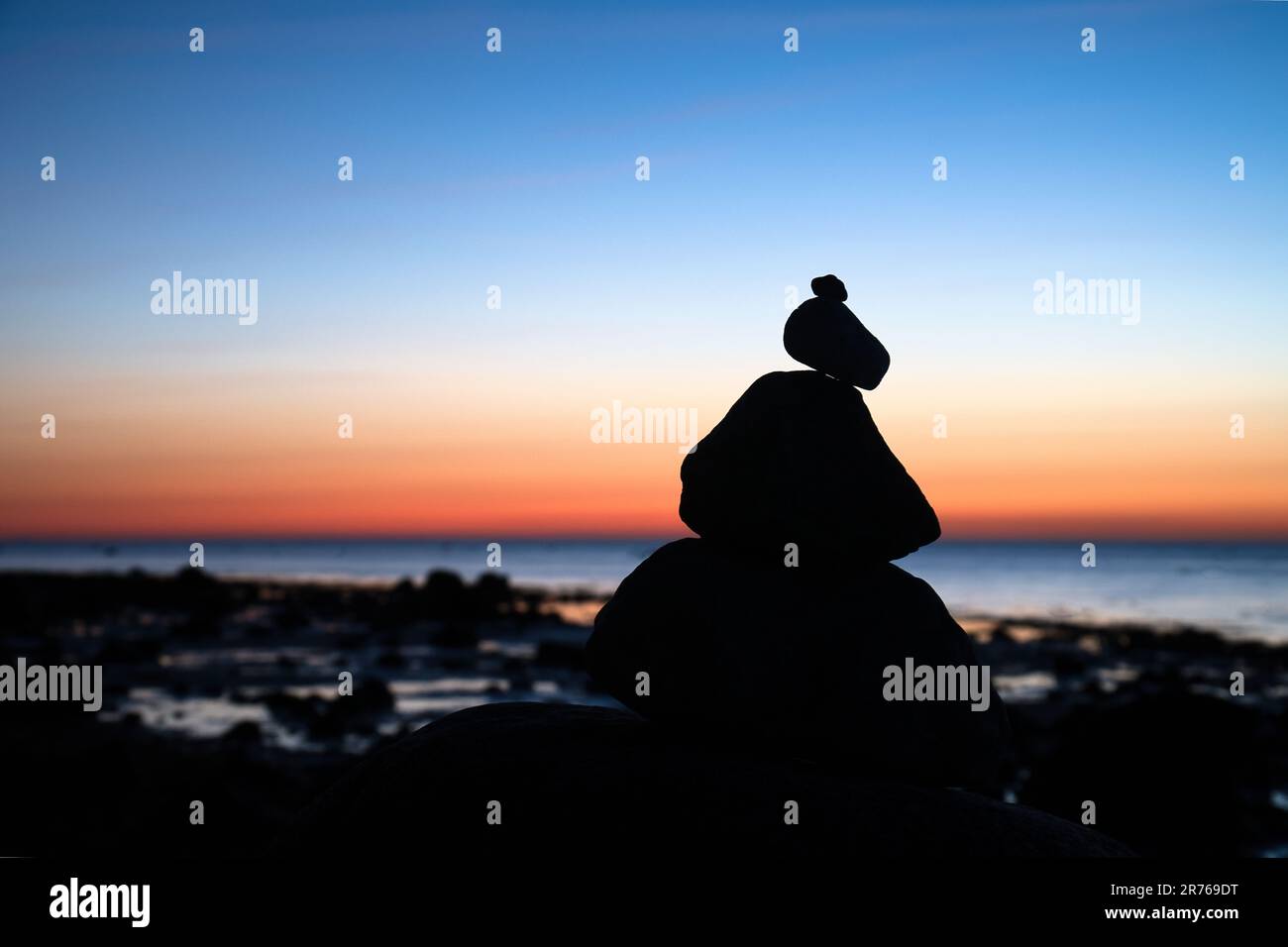 Steinpyramide an der Ostsee mit Blick auf das Meer bei Sonnenuntergang und Blue Hour. Steine als Silhouette. Spirituelle Sichtweise. Landschaftsaufnahmen von Poel Island Stockfoto