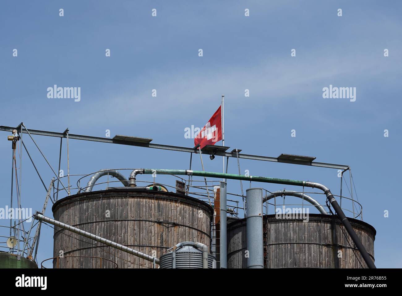Verkürzte Holzsilos mit Schweizer Flagge am blauen Himmel. Speicherplatz kopieren. Stockfoto
