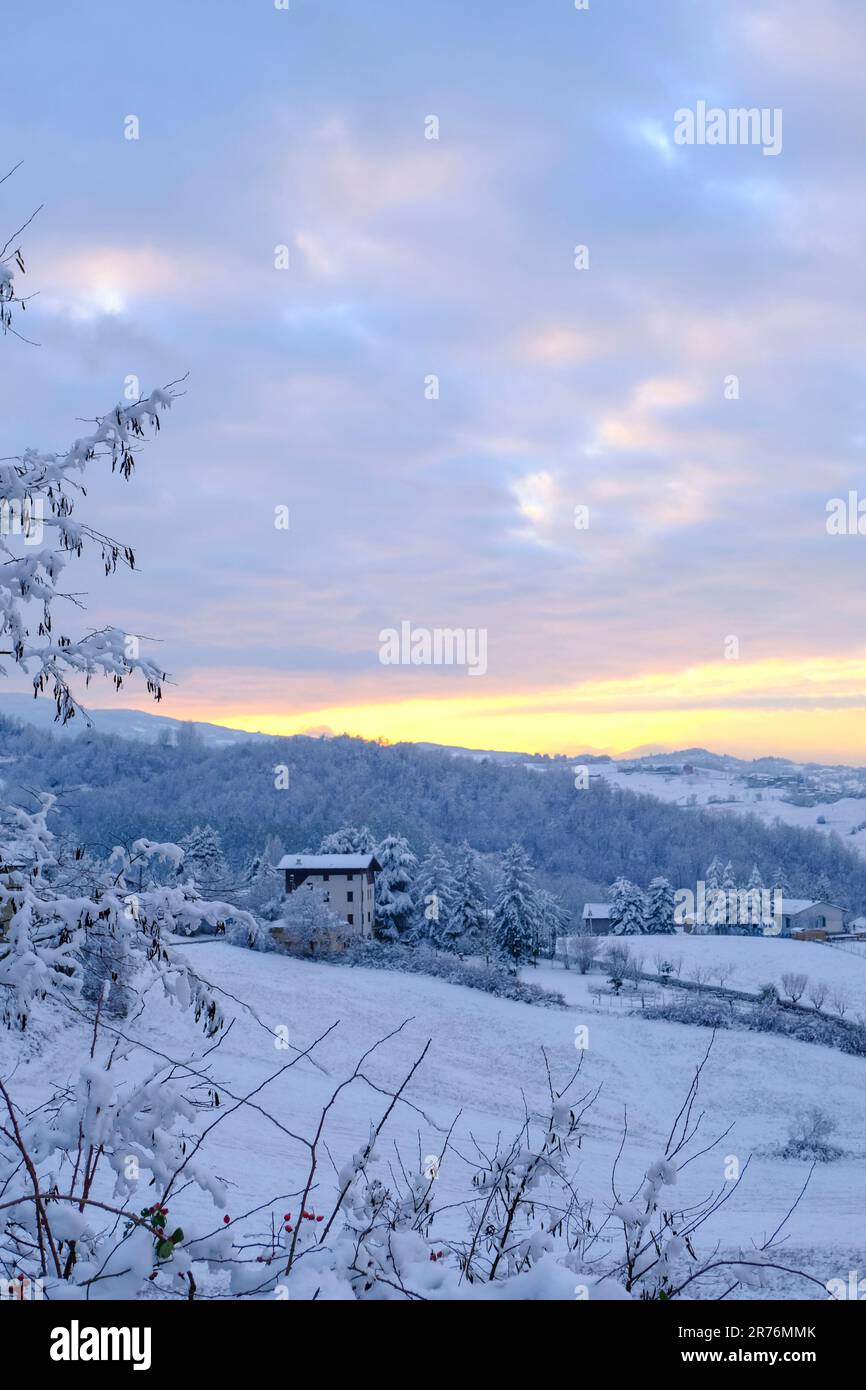 Schneesturm in den Bergen bei Sonnenuntergang. Schneebedeckte Hügel, Berge, Dorf, Natur, Horizont. Natürlicher Hintergrund. Appennino-Tosco-emiliano Stockfoto