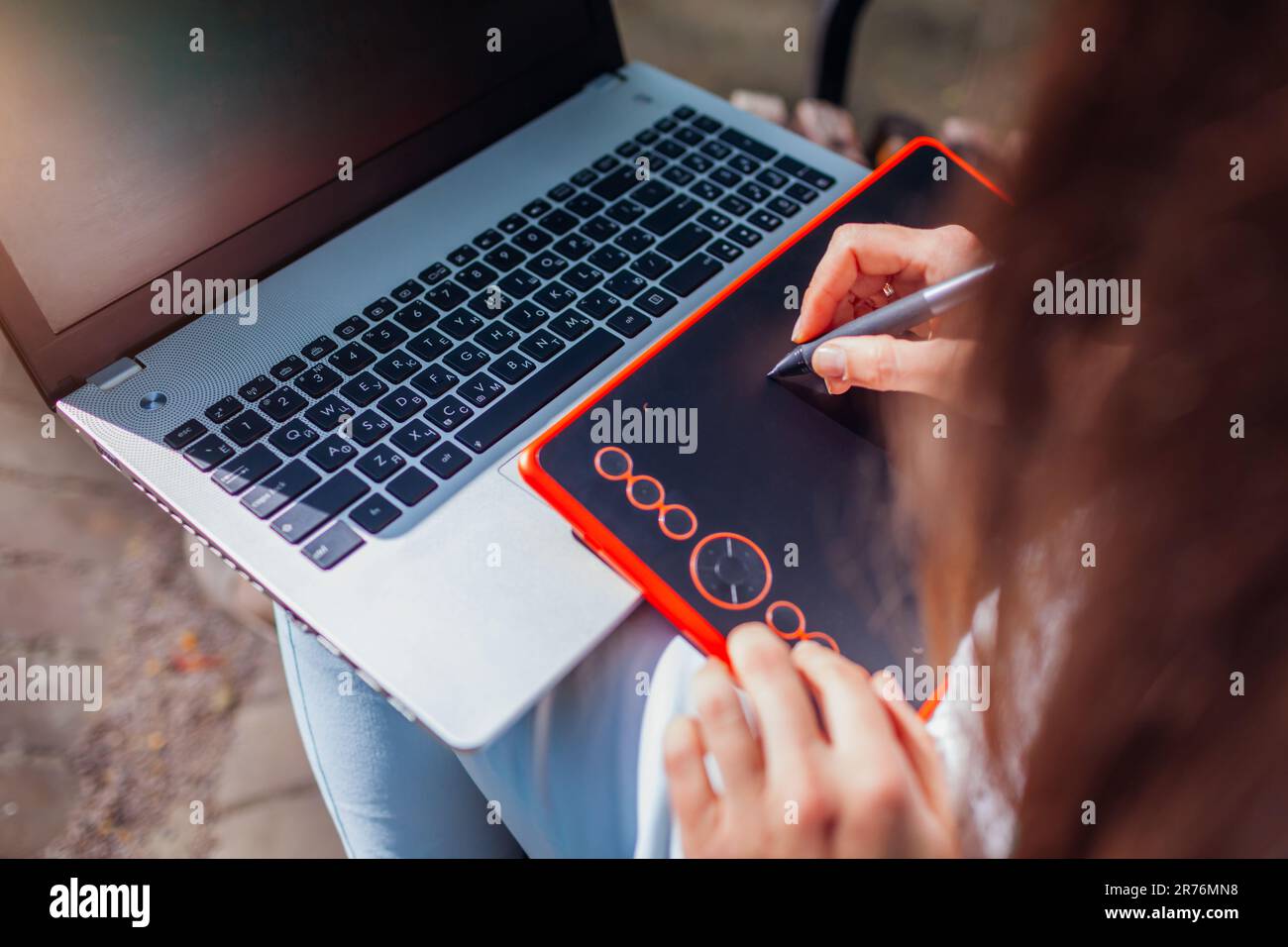 Frau, die im Freien mit Notebook und Tablet arbeitet. Grafikdesigner, der Remote arbeitet. Zeichnen mit dem Stift. Draufsicht Stockfoto