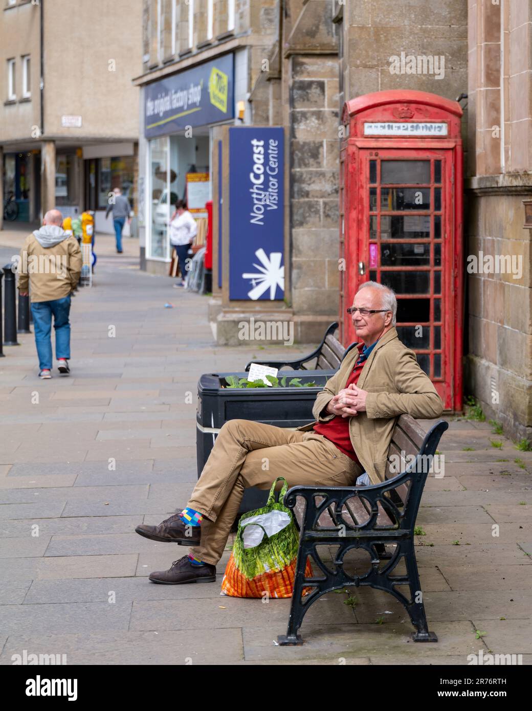 9. Juni 2023 Thurso, Schottland. Das ist ein Mann, der auf einer Straßenbank sitzt und die Sonne im Einkaufsviertel von Thurso genießt. Stockfoto