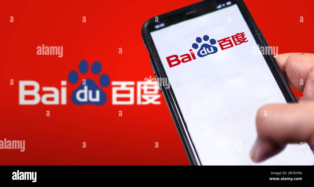 Peking, CN, Februar 2023: Eine Hand, die ein Telefon hält und die Baidu-Website auf dem Bildschirm angezeigt wird. Roter Hintergrund mit verschwommenem Baidu-Logo. Baidu ist ein chinesischer Multina Stockfoto