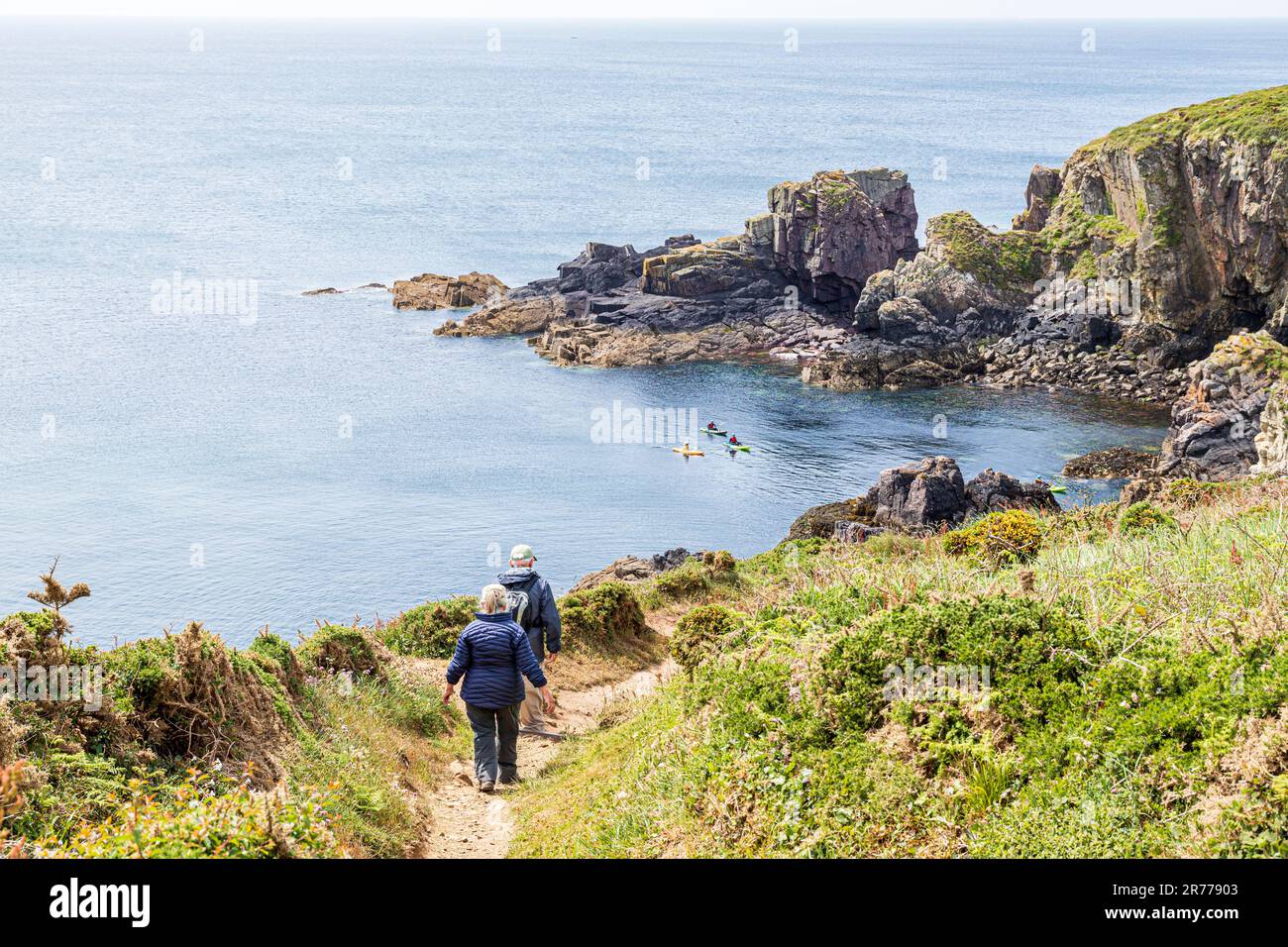 Spaziergänger auf dem Pembrokeshire Coast Path National Trail und Kanufahrer auf der St Non's Bay, der Halbinsel St. David im Pembrokeshire Coast National Park Stockfoto