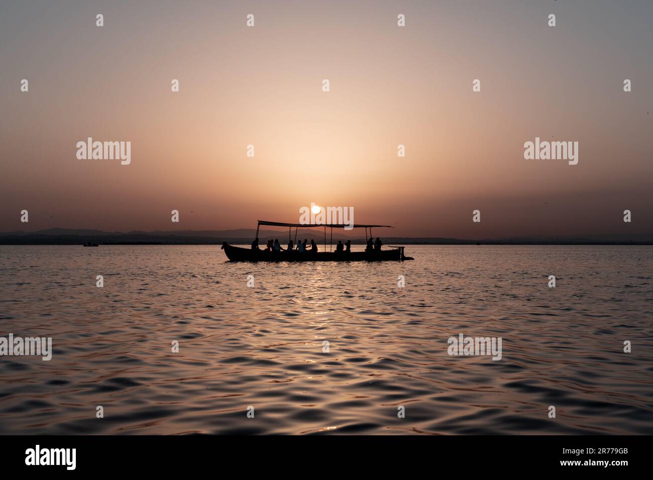 Das Boot mit Hintergrundbeleuchtung navigiert in ruhigen Gewässern mit einem sanften Sonnenuntergang. Albufera, Valencia, Spanien. Stockfoto