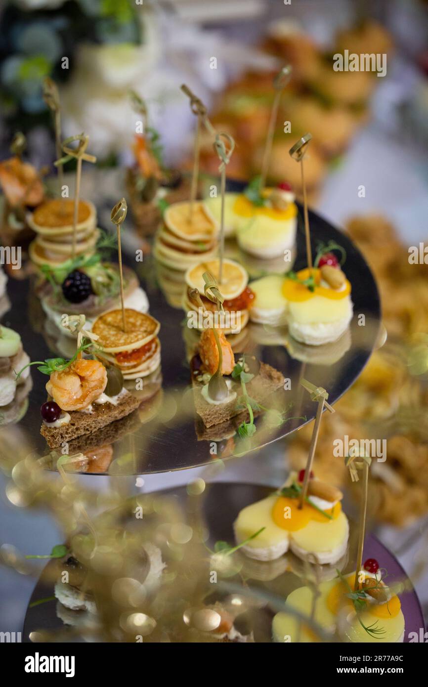 Verschiedene Snacks und Kanapees auf einem Metallständer auf dem Buffettisch. Stockfoto