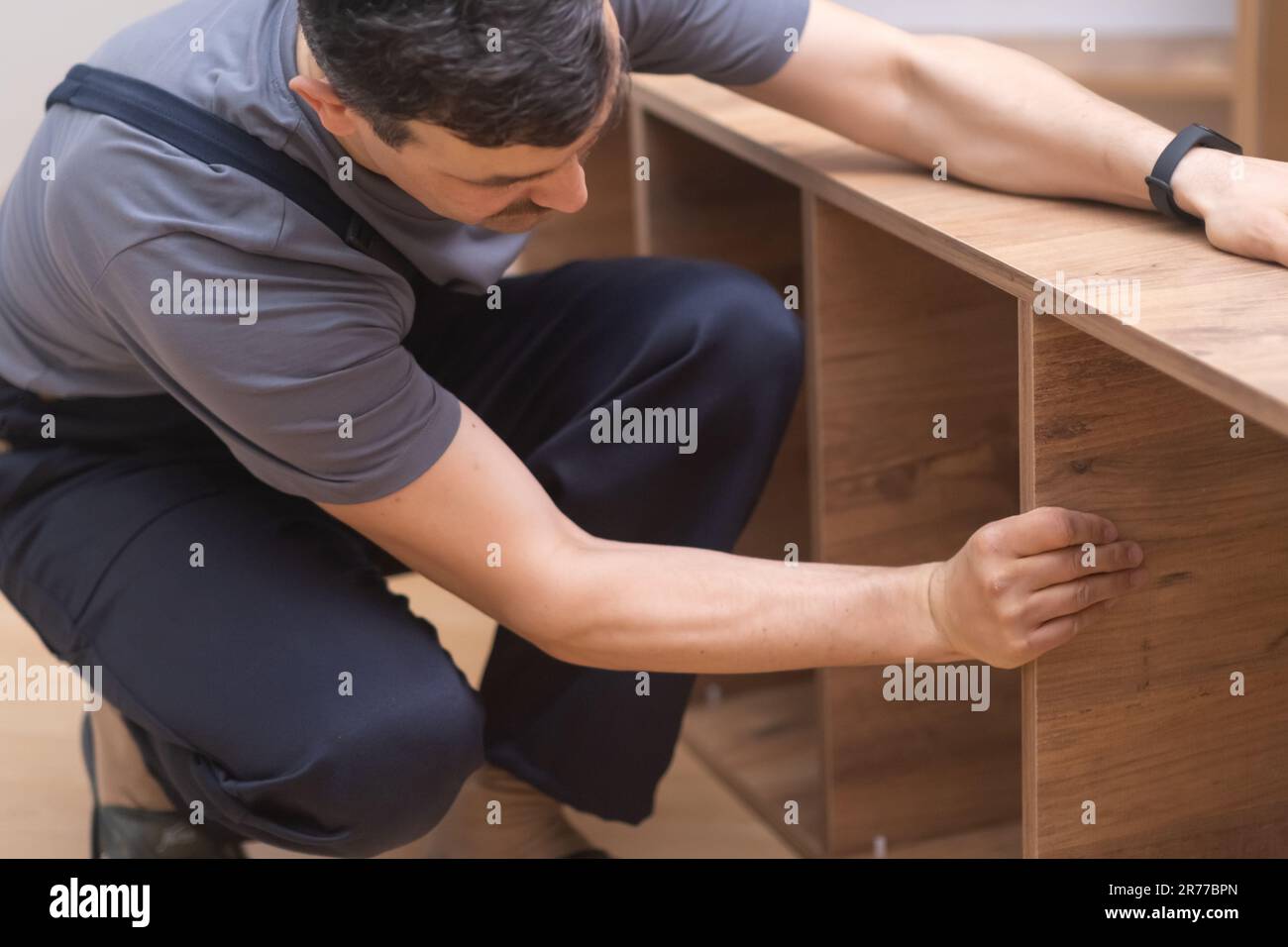Kundenspezifische Möbelherstellung und Fixiermann in Overalls zur Installation von Regalen auf Holzregalen Stockfoto
