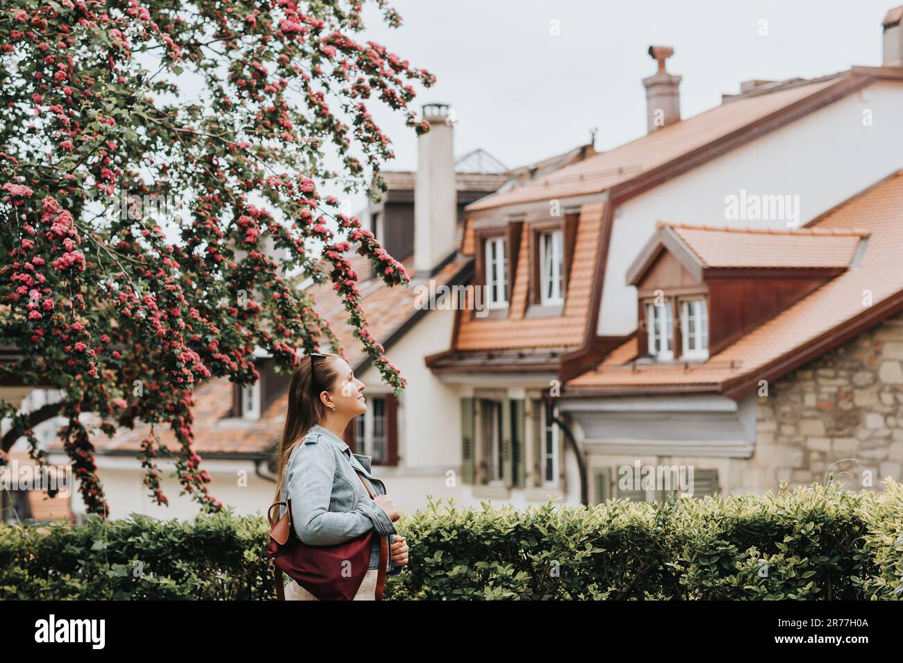 Junge schöne Frau genießt den Frühling in der Stadt, Modemädchen trägt Rucksack und Jeansjacke. Bild aufgenommen in Lausanne, Schweiz Stockfoto