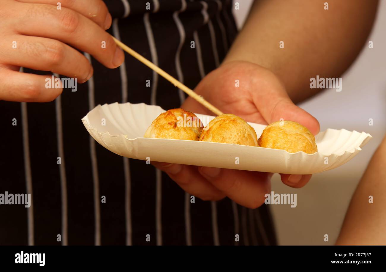 Koch am Stand der japanischen Botschaft steckt eine Portion frittierter Teigtaschen in eine Pappschachtel, die ein Kunde mit nach Hause nehmen kann. Stockfoto