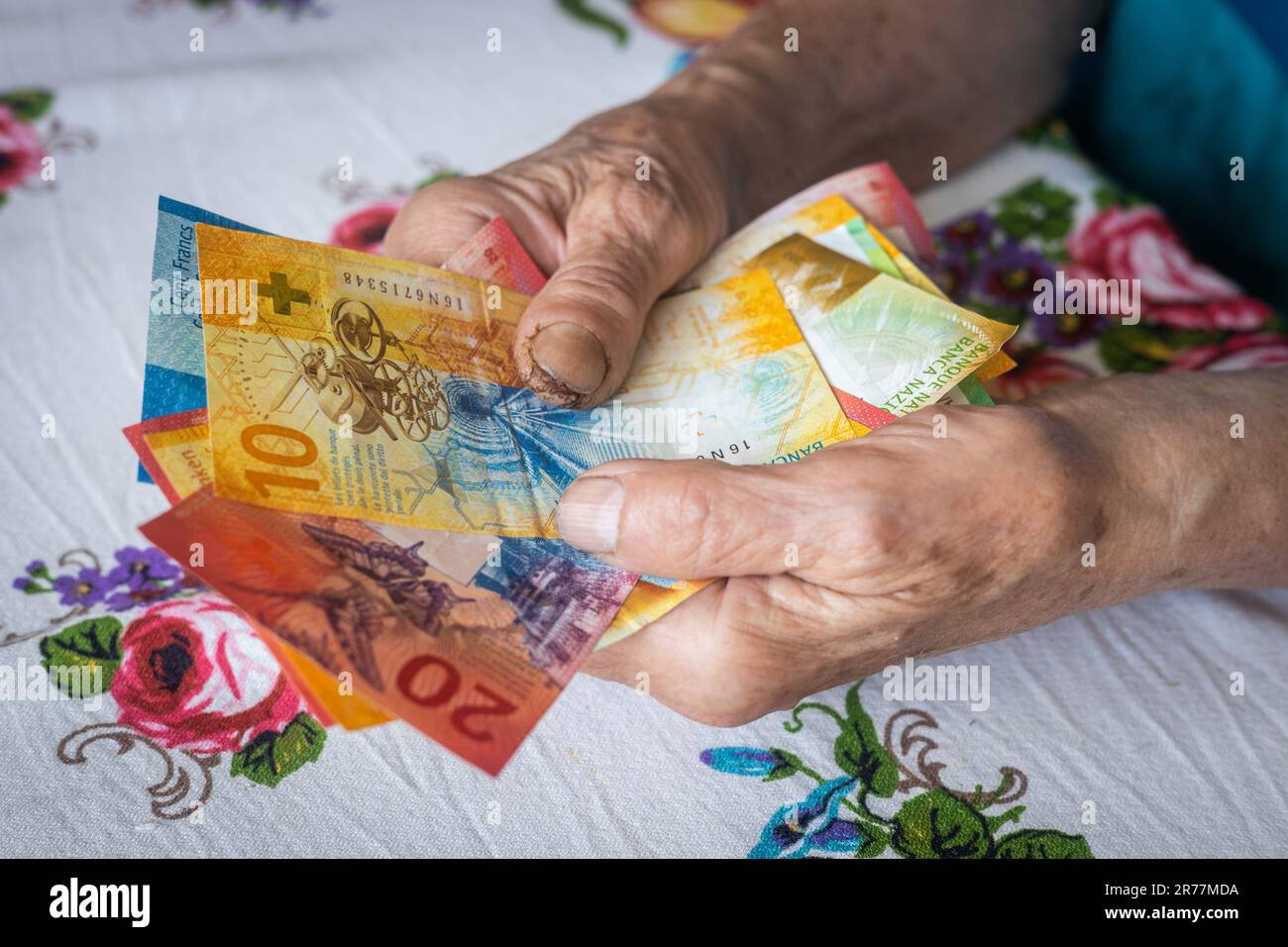 Die Rentnerin hält eine Banknote mit niedrigem Nennwert in ihren Händen, die Lebenshaltungskosten für einen älteren Bürger in der Schweiz, die Renten und die Schweizer Sozialversicherung Stockfoto