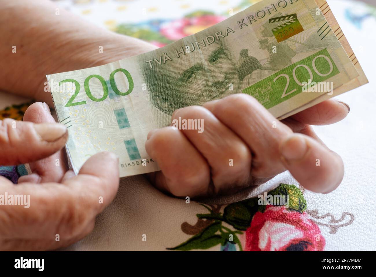 Eine schwedische Rentnerin hält eine Banknote mit niedrigem Nennwert in ihren Händen, die Lebenshaltungskosten für einen älteren in Schweden, die Renten und die schwedischen Sozialversicherungen Stockfoto