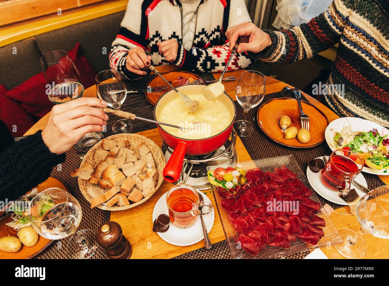 Freunde essen Käsefondue in einem gemütlichen, traditionellen schweizer Restaurant Stockfoto