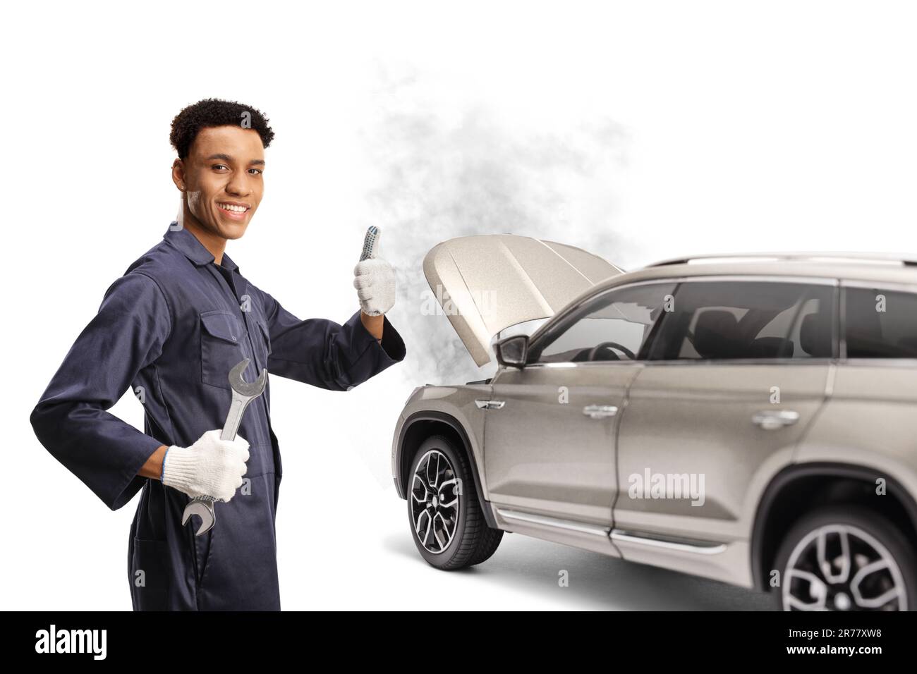afroamerikanischer Automechaniker, der einen Schraubenschlüssel hält und vor einem kaputten SUV die Daumen hochdrückt, isoliert auf weißem Hintergrund Stockfoto