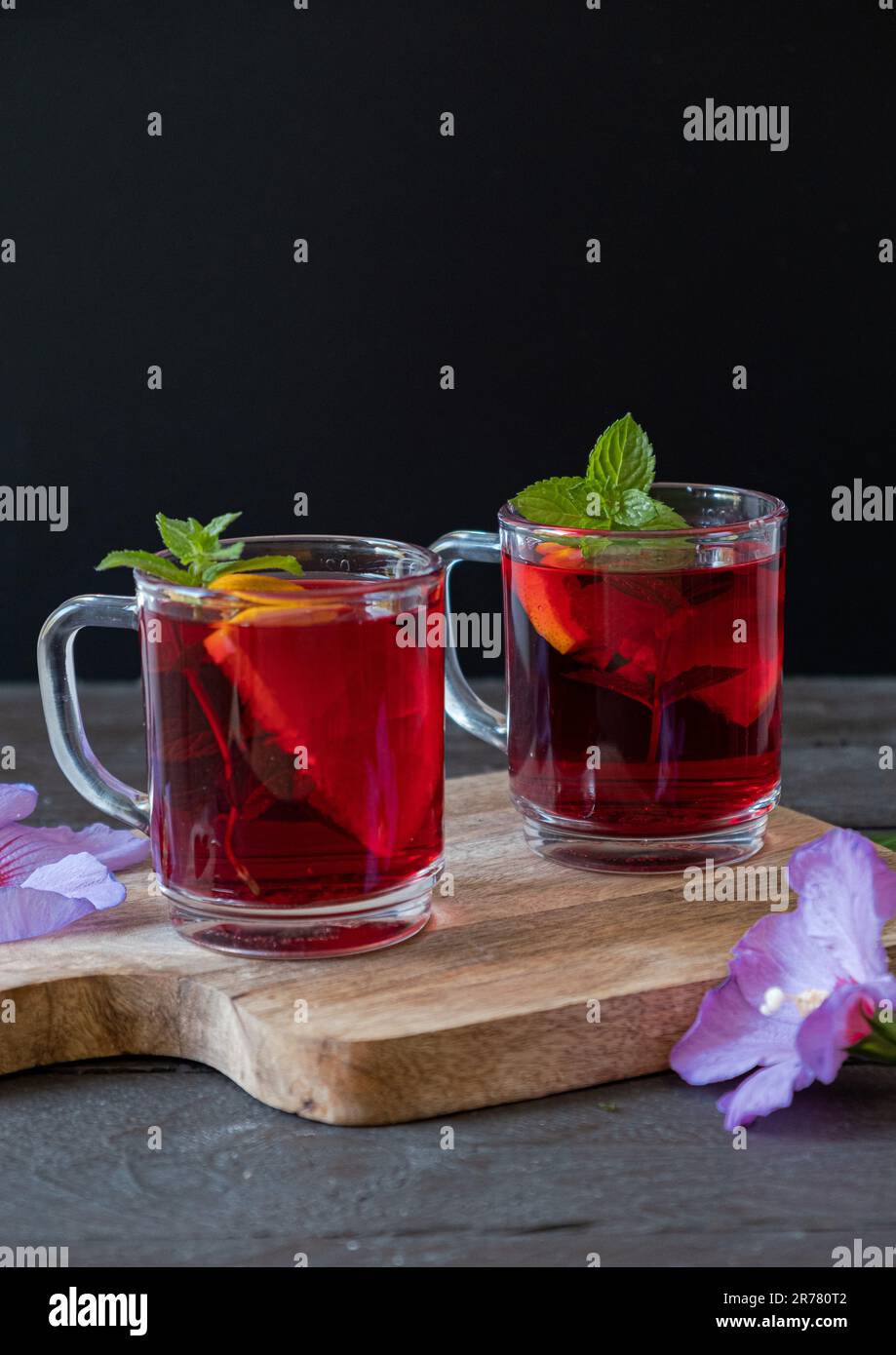 Roter heißer Hibiskus-Tee in einer Glasbecher auf einem Holztisch, vertikales Foto Stockfoto