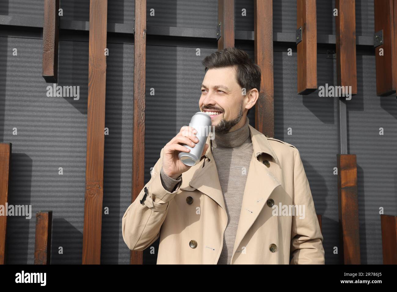 Ein glücklicher Mann mit einer silbernen Blechdose und einem Getränk im Freien Stockfoto