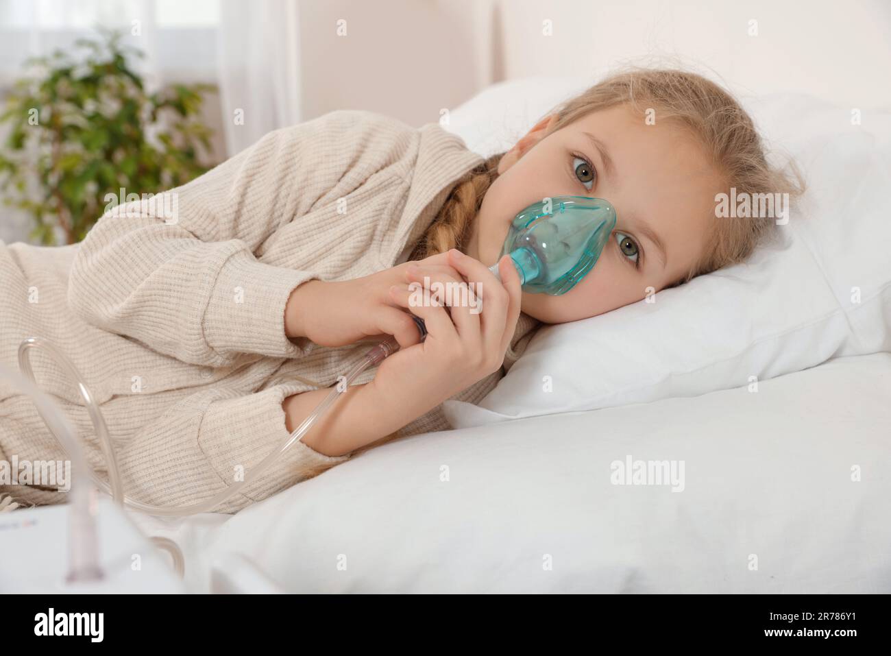 Kleines Mädchen, das zu Hause Vernebler zur Inhalation am Bett benutzt Stockfoto