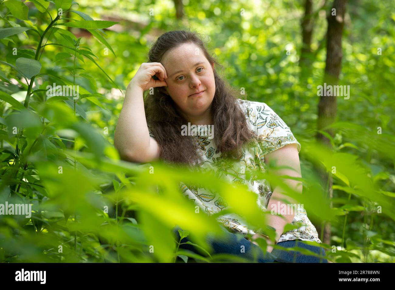 Asheville, North Carolina, USA. 10. Juni 2023. Caroline Dempsey, 26, die aufgrund des Down-Syndroms eine Entwicklungsbehinderung hat, lässt nicht zu, dass ihre Herausforderung sie von ihrer Liebe zu Natur und Kunst abhält. Die junge Künstlerin konnte eine Reihe ihrer Gemälde verkaufen und hofft, dass sie mehr verkaufen kann, wenn das Interesse an Folk Art wächst.Bild: Caroline in einem beliebten Naturschutzgebiet am Asheville Botanical Garden der University of North Carolina (Kredit: © Robin Rayne/ZUMA Press Wire) – NUR REDAKTIONELLE VERWENDUNG! Nicht für den kommerziellen GEBRAUCH! Stockfoto