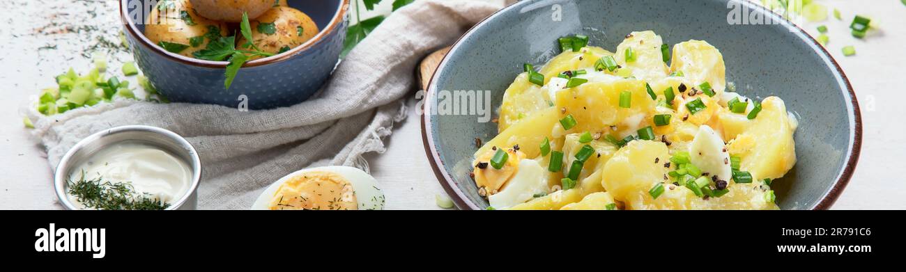 Salat aus Kartoffeln, Eiern, grünen Zwiebeln und Mayonnaise auf einem Teller auf weißem Hintergrund, Draufsicht. Speicherplatz kopieren. Stockfoto