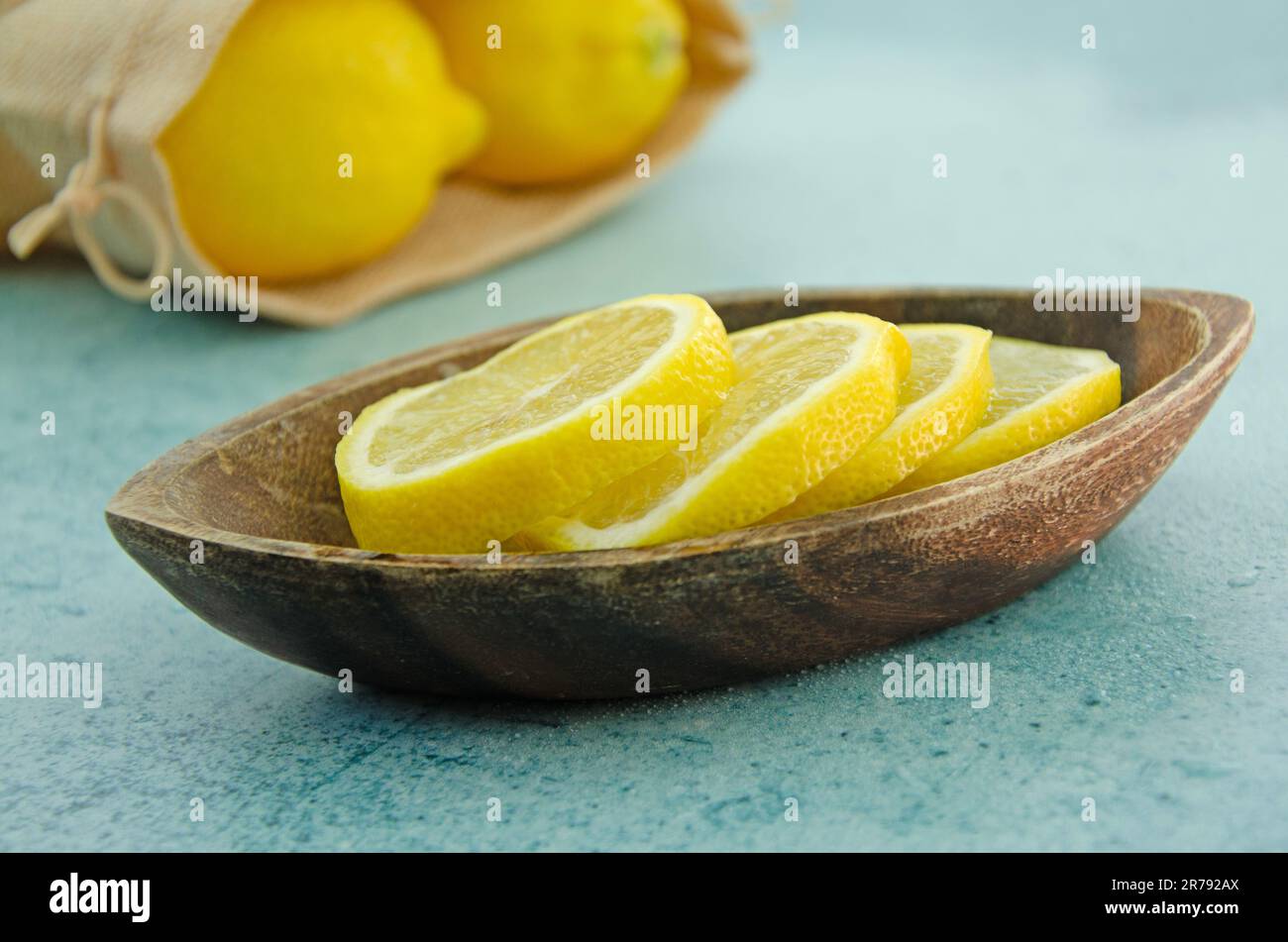 Nahaufnahme von Zitronenscheiben in einer Holzschüssel. Zitronen in einer hessischen Tasche Stockfoto