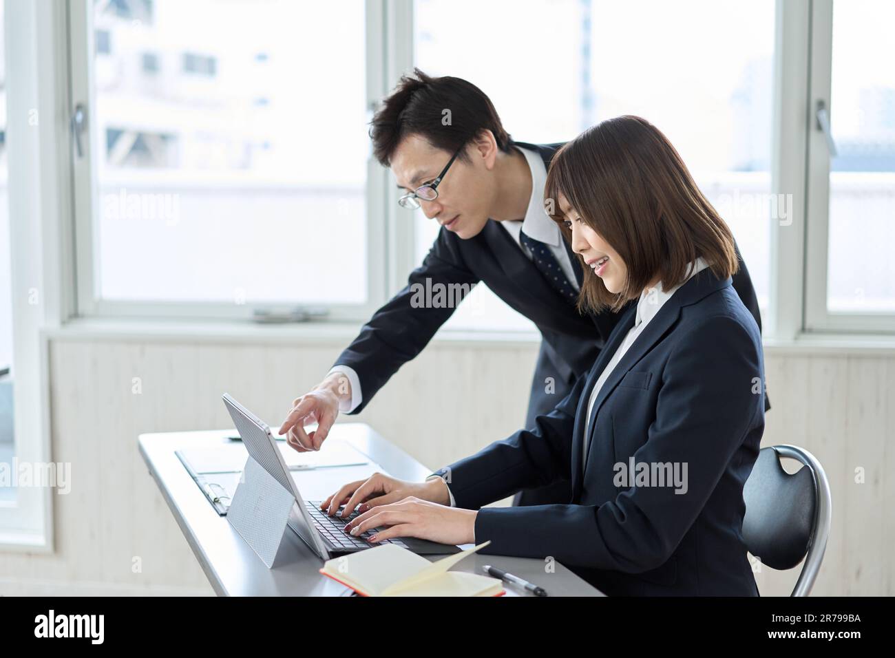 Asiatischer Geschäftsmann, der den Computer seines Untergebenen unterrichtet Stockfoto