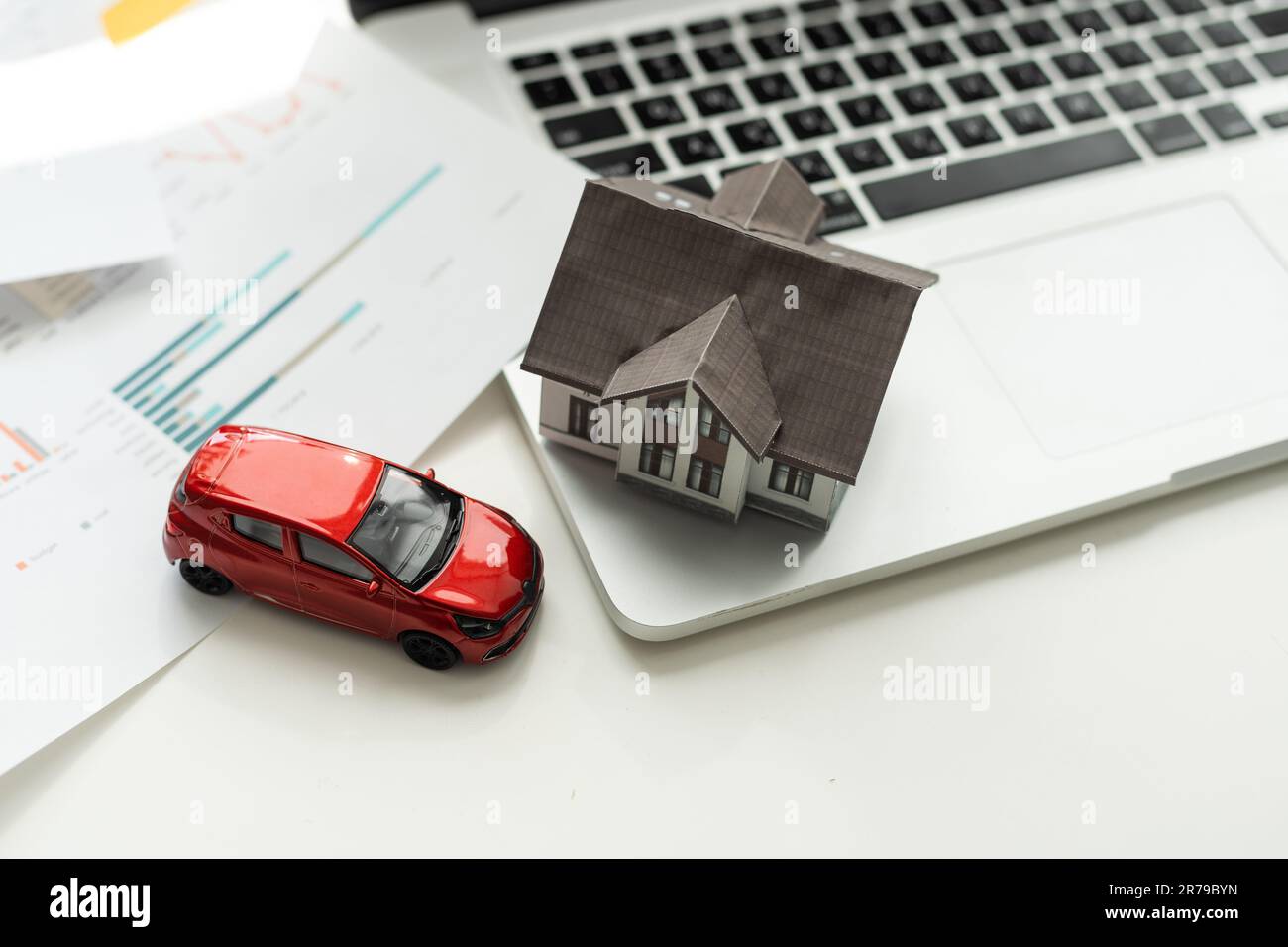 Versicherungshaus, Auto und Familie leben Konzept. Der Versicherungsvertreter stellt die Spielzeuge vor, die die Deckung symbolisieren. Stockfoto
