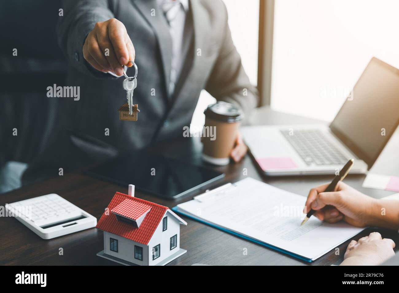 Hausverkaufs- und Hausversicherungskonzept. Immobilienmakler, der Frau Hausschlüssel übergibt und den Kunden bittet, die Dokumente zu unterzeichnen, um den Vertrag rechtmäßig zu machen Stockfoto