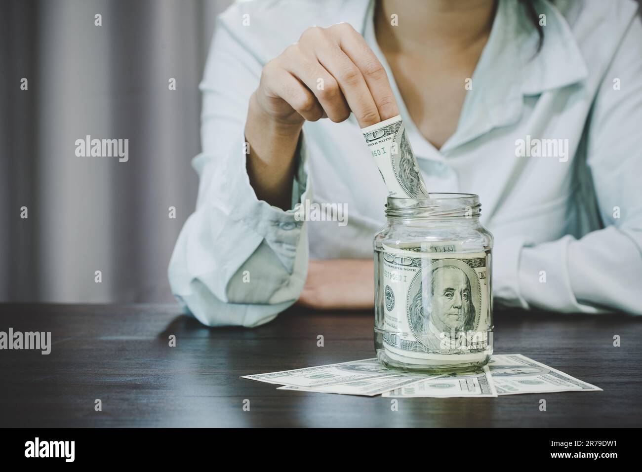 Frau, die Dollarscheine hält, schafft es, das Geld zu teilen, um Geld zu sparen und es zu investieren, damit es noch weiter wächst. Geld sparen und Geld investieren Stockfoto